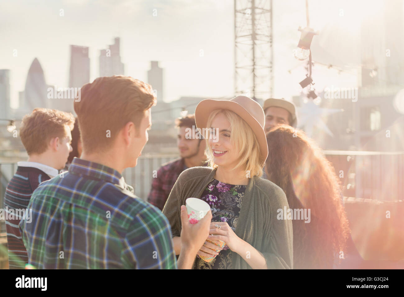 Giovane uomo e donna bere e parlare al partito sul tetto Foto Stock
