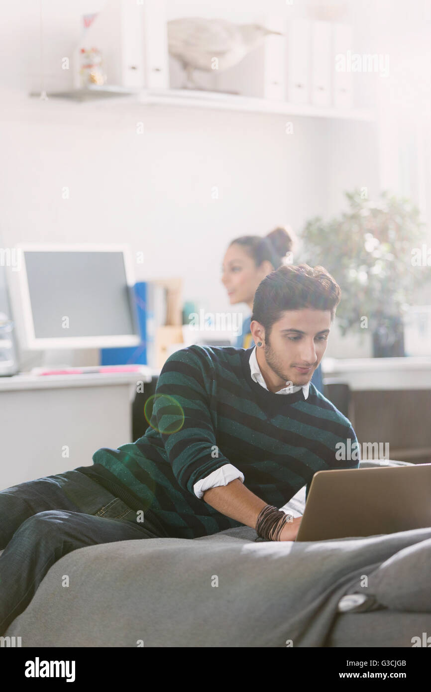 Giovane uomo utilizzando laptop sul letto Foto Stock