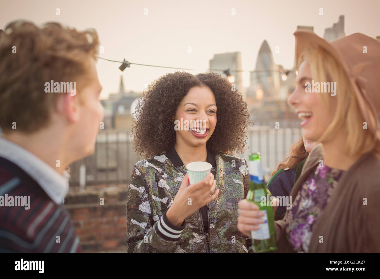 Giovani amici adulti bere e godere di partito sul tetto Foto Stock