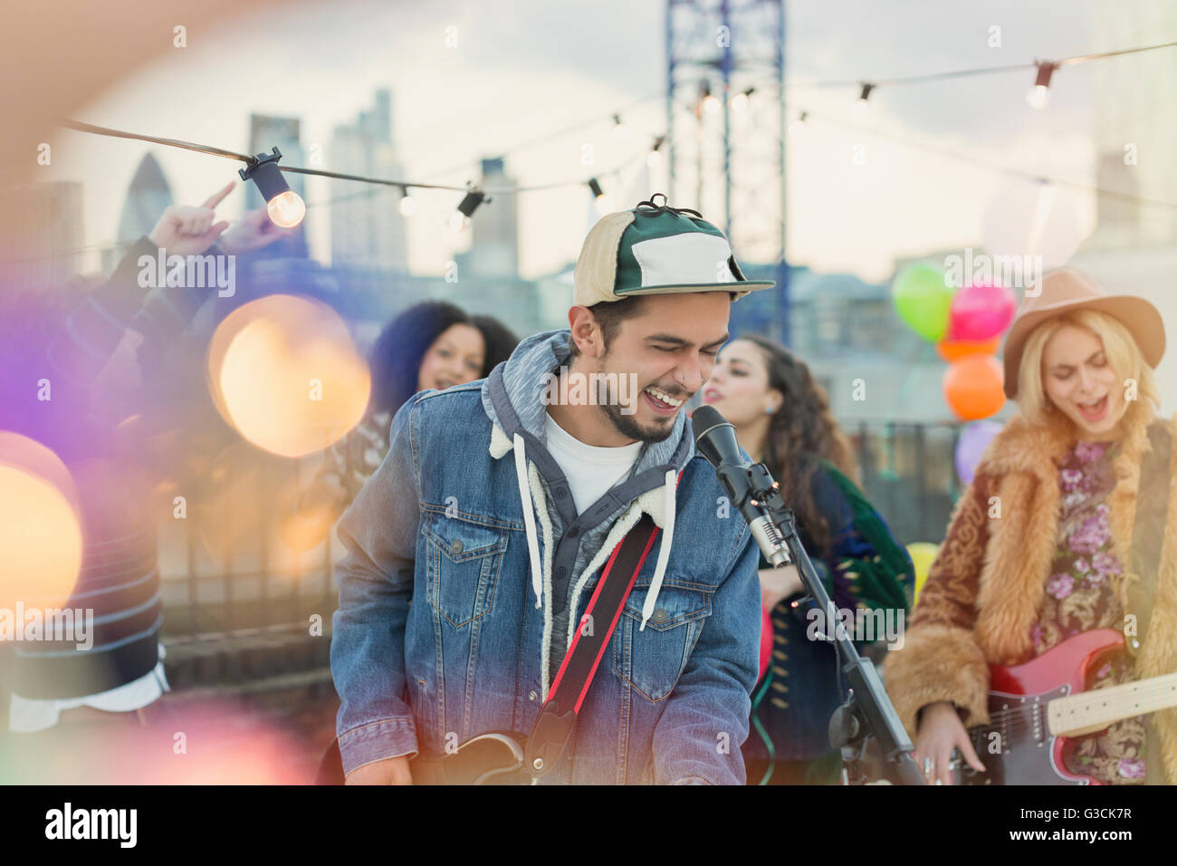 Musicista entusiasta a suonare la chitarra e cantare in parte sul tetto Foto Stock