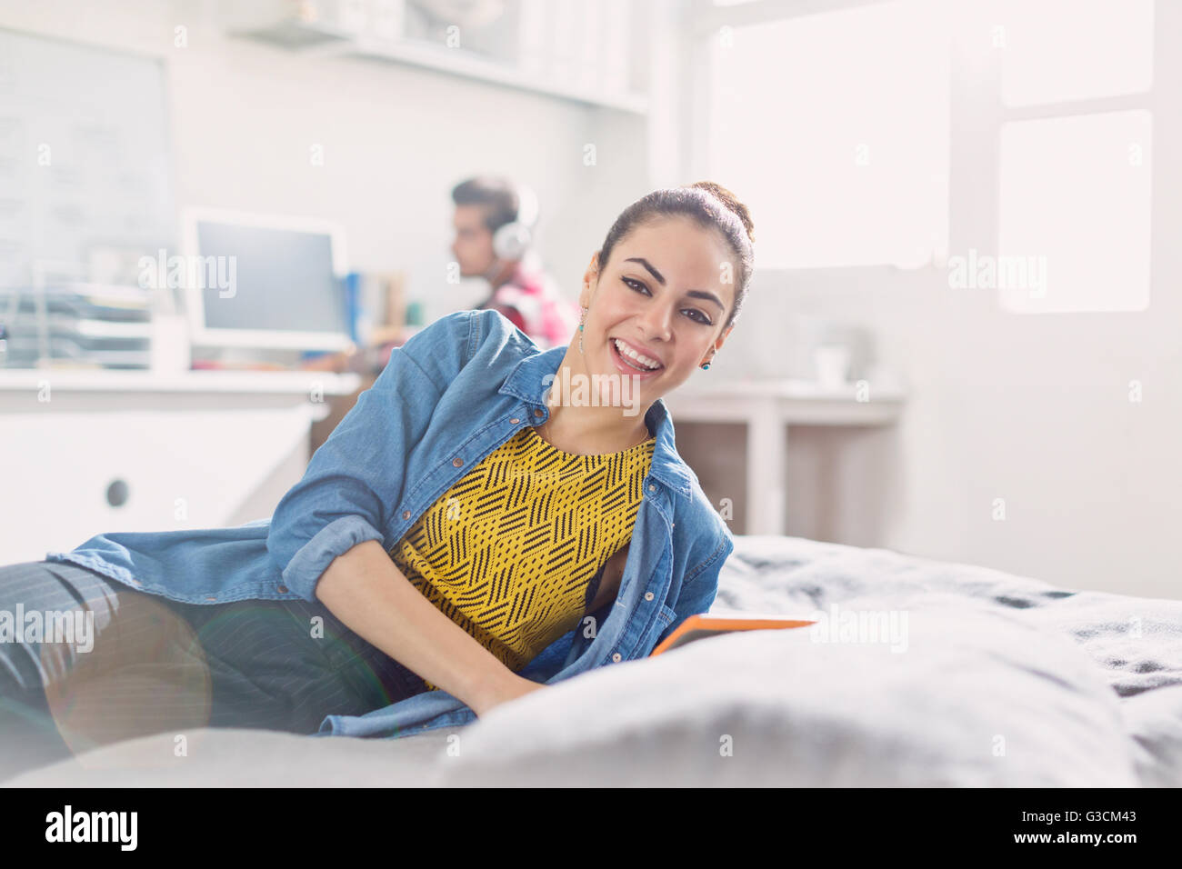 Ritratto sorridente giovane donna adulta la lettura sul letto Foto Stock