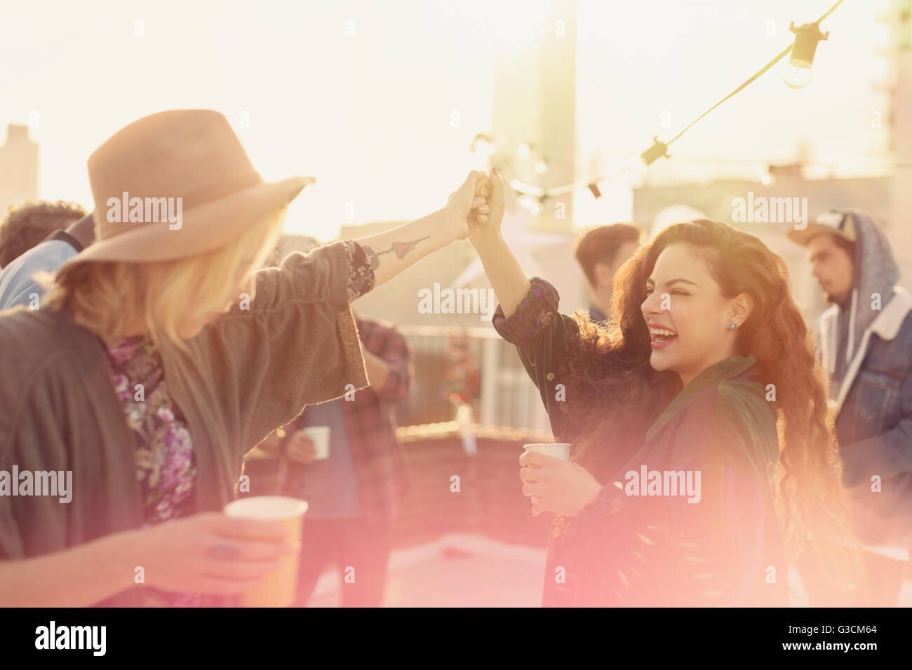 Entusiasta di giovani donne adulte ballare e bere alla festa sul tetto Foto Stock