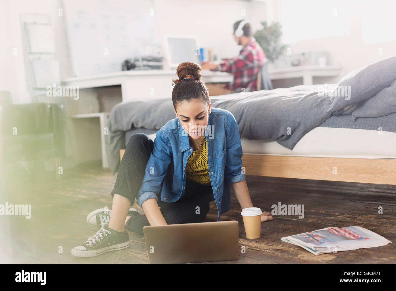 Collegio femminile studente con caffè utilizzando laptop sul pavimento della camera Foto Stock