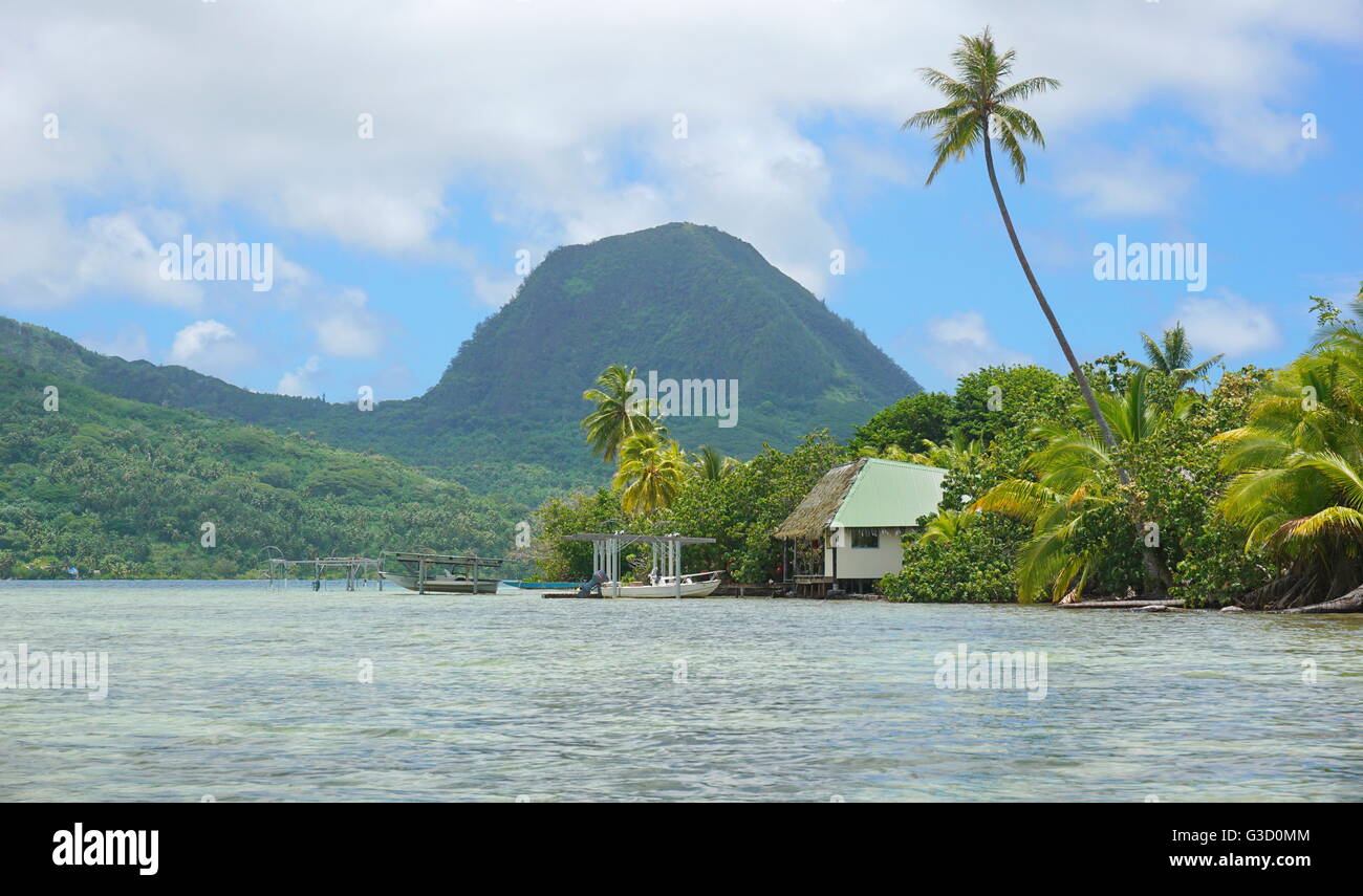Riva di un isolotto con una casa e il monte Moua Tapu in background, Huahine isola, a sud Pacifico, Polinesia Francese Foto Stock