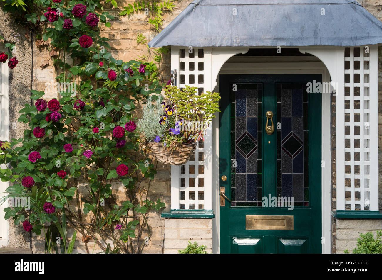 Rose rosse sulla parte anteriore di una casa di pietra. Bampton, Oxfordshire, Inghilterra Foto Stock