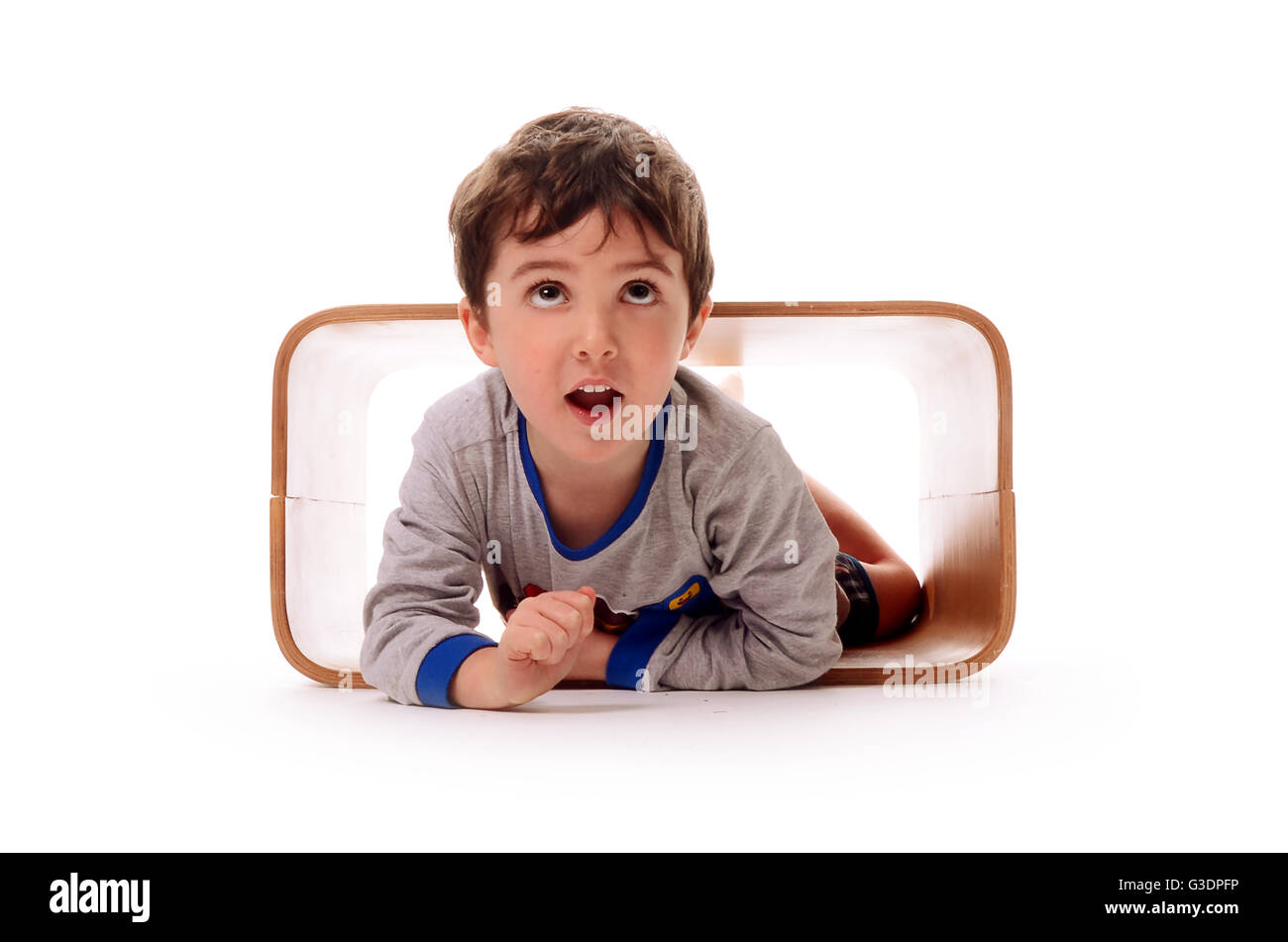 Ragazzo giocando in una scatola di legno, esplorando l'ambiente Foto Stock