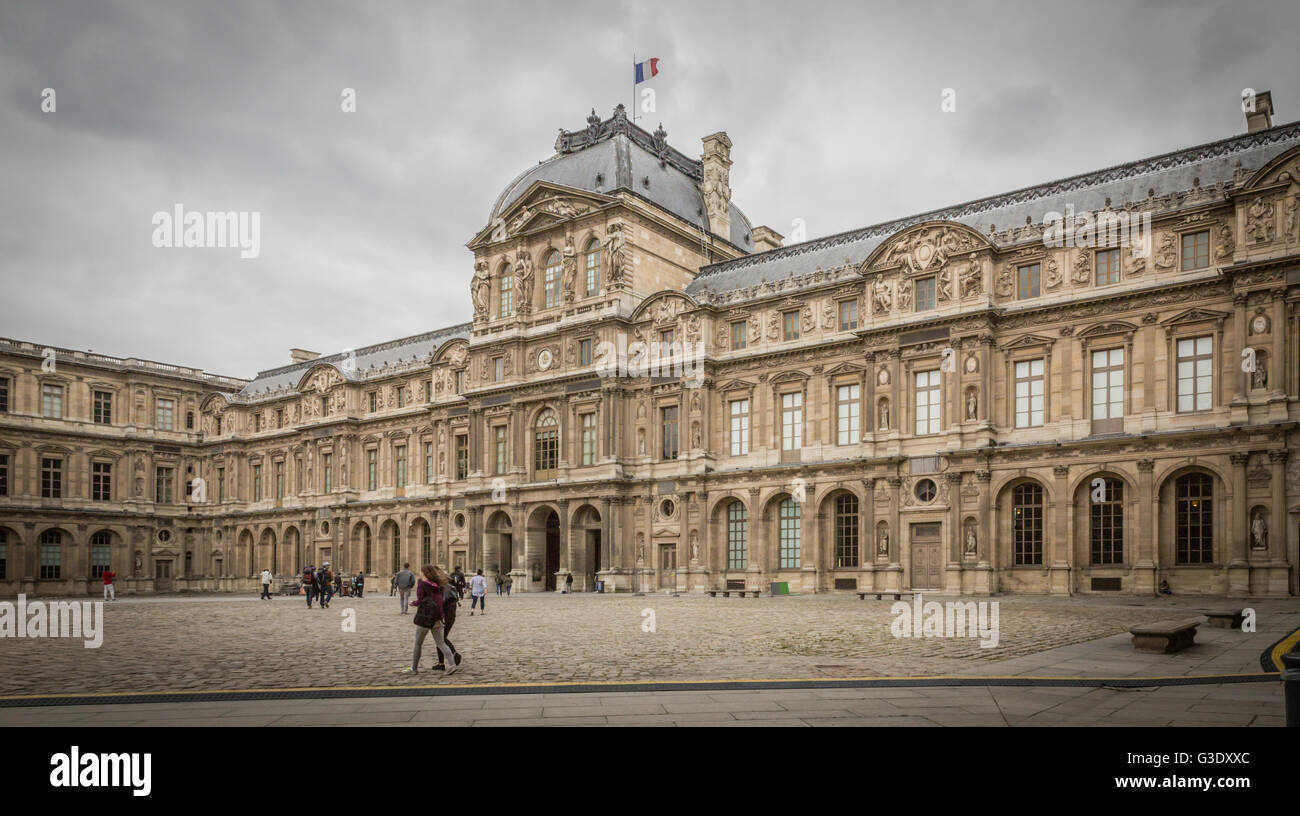 I turisti passeggiano nel cortile del museo del Louvre, una volta a palazzo reale e ora un museo a Parigi e una grande attrazione turistica. Foto Stock