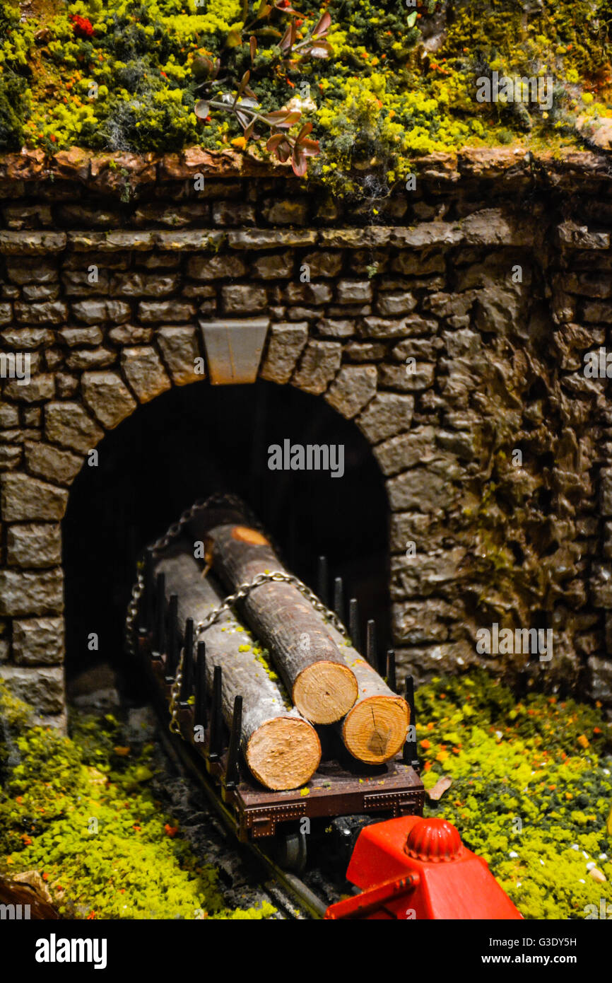 Giocattolo impilati i registri di legname su rampa auto va in pietra tunnel del treno a diorama per il modello di treno Foto Stock