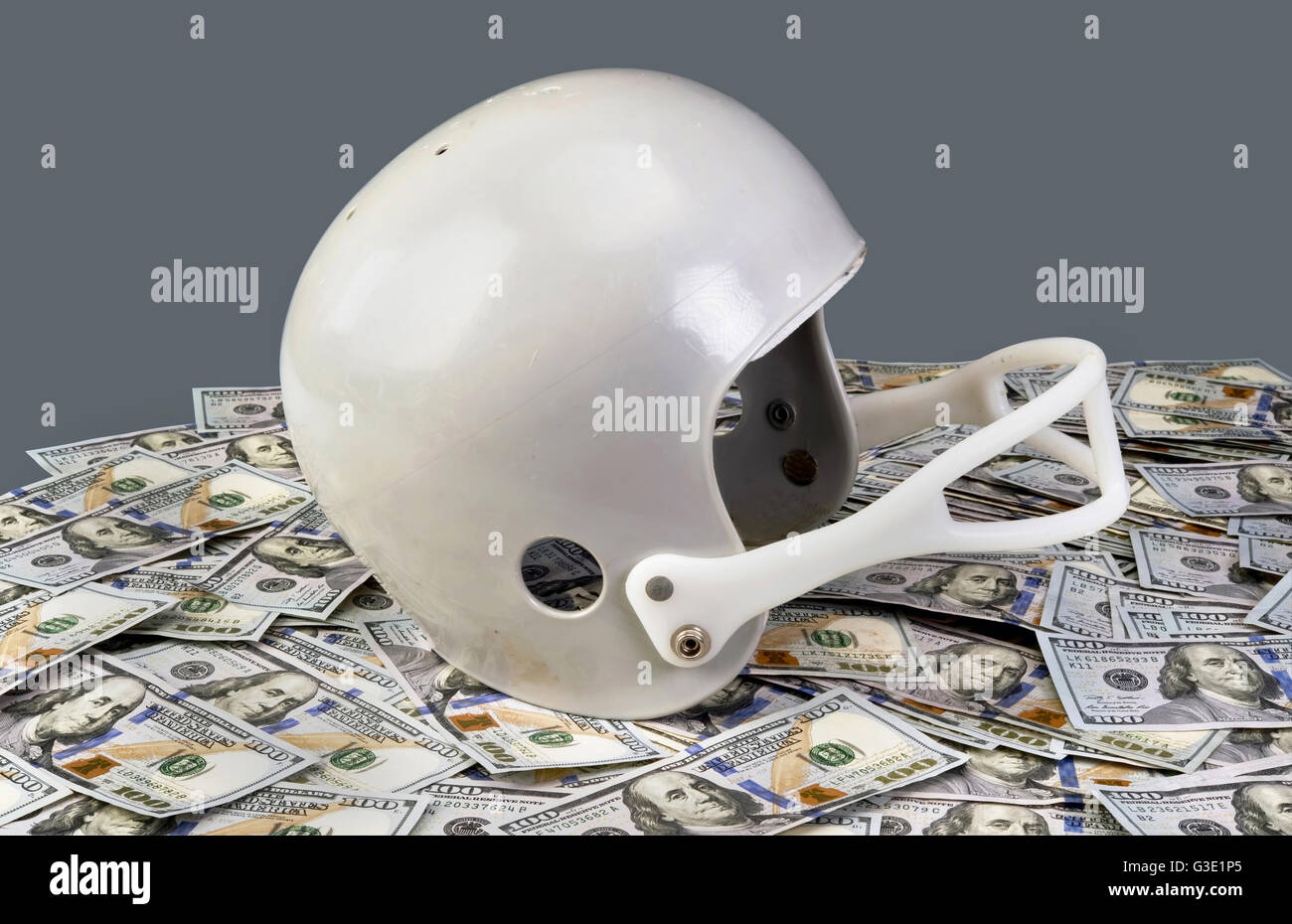 Il football americano casco sulla sommità pila di centinaia di fatture del dollaro. Foto Stock