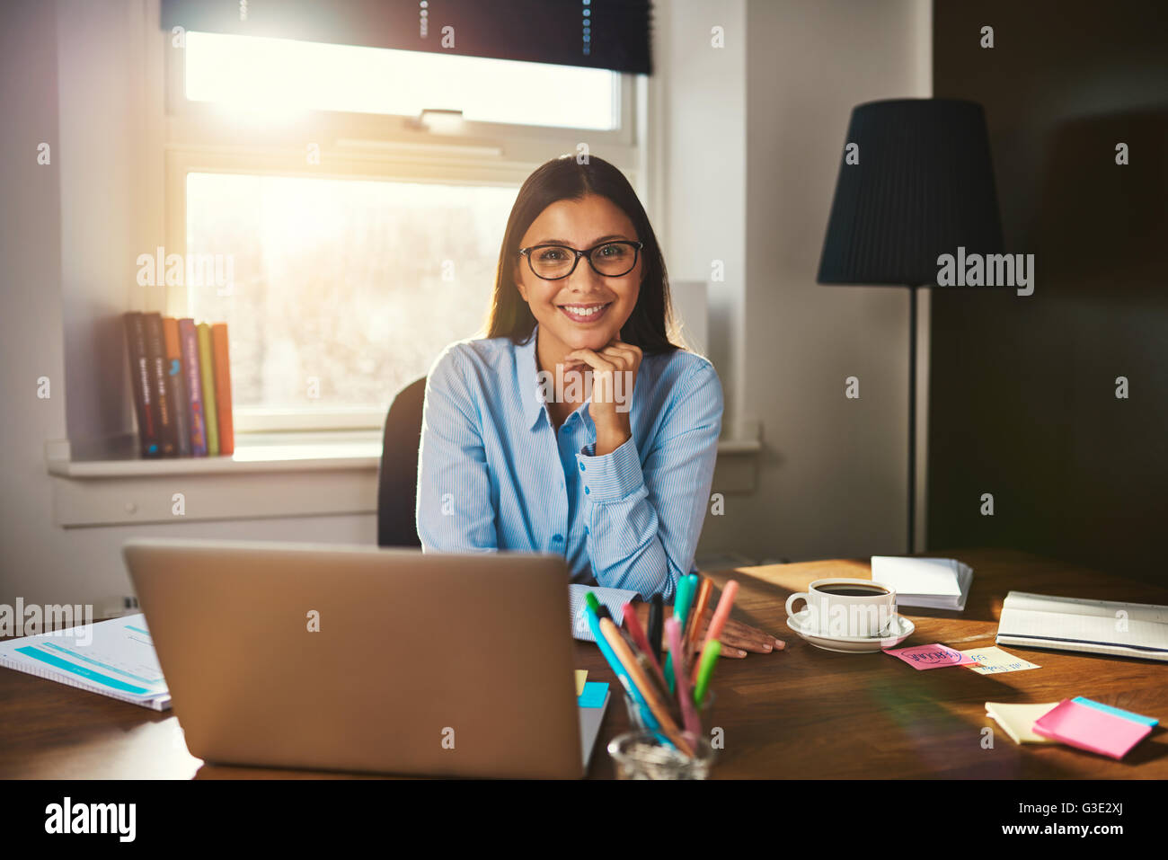 Imprenditore femmina seduto alla scrivania sorridente in telecamera Foto Stock