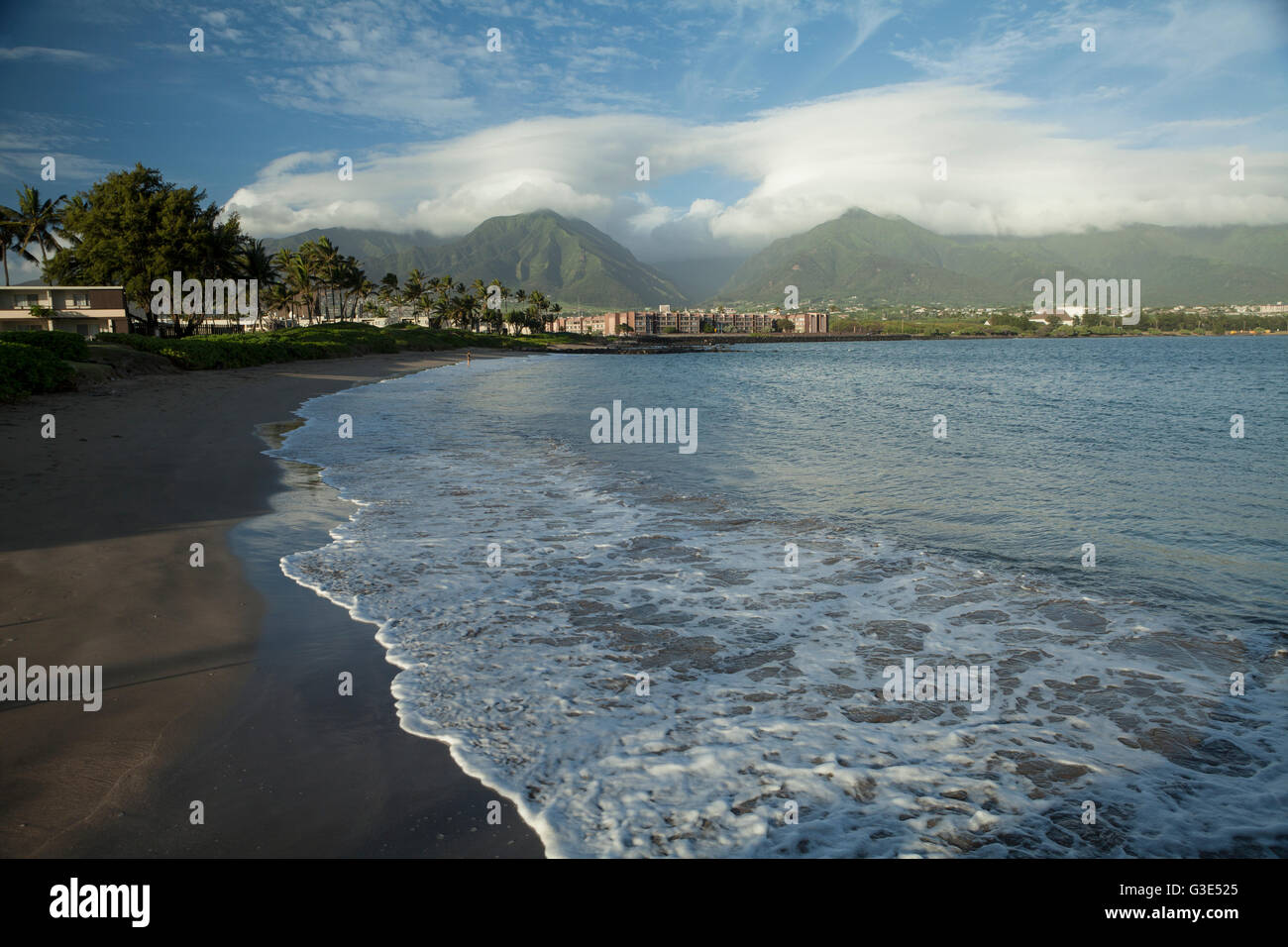 Spiaggia di sabbia nera, condomini e alberghi, Amala Beach, con Iao valle in background; Kahalui, Maui, Hawaii, STATI UNITI D'AMERICA Foto Stock