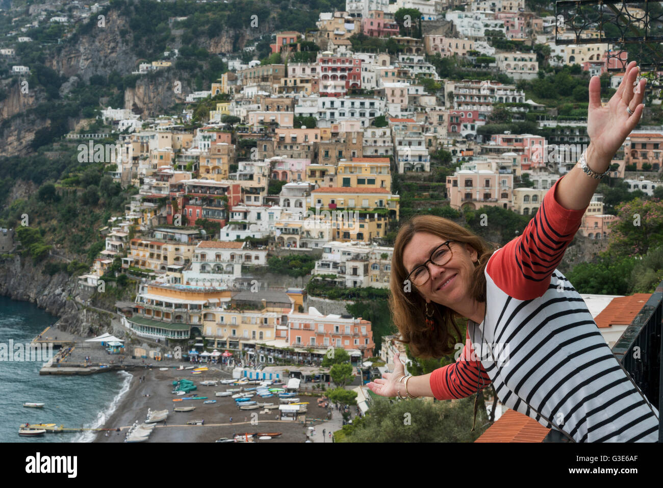 Una donna in posa con una vista degli edifici lungo la costa di Amalfi e Positano, Campania, Italia Foto Stock