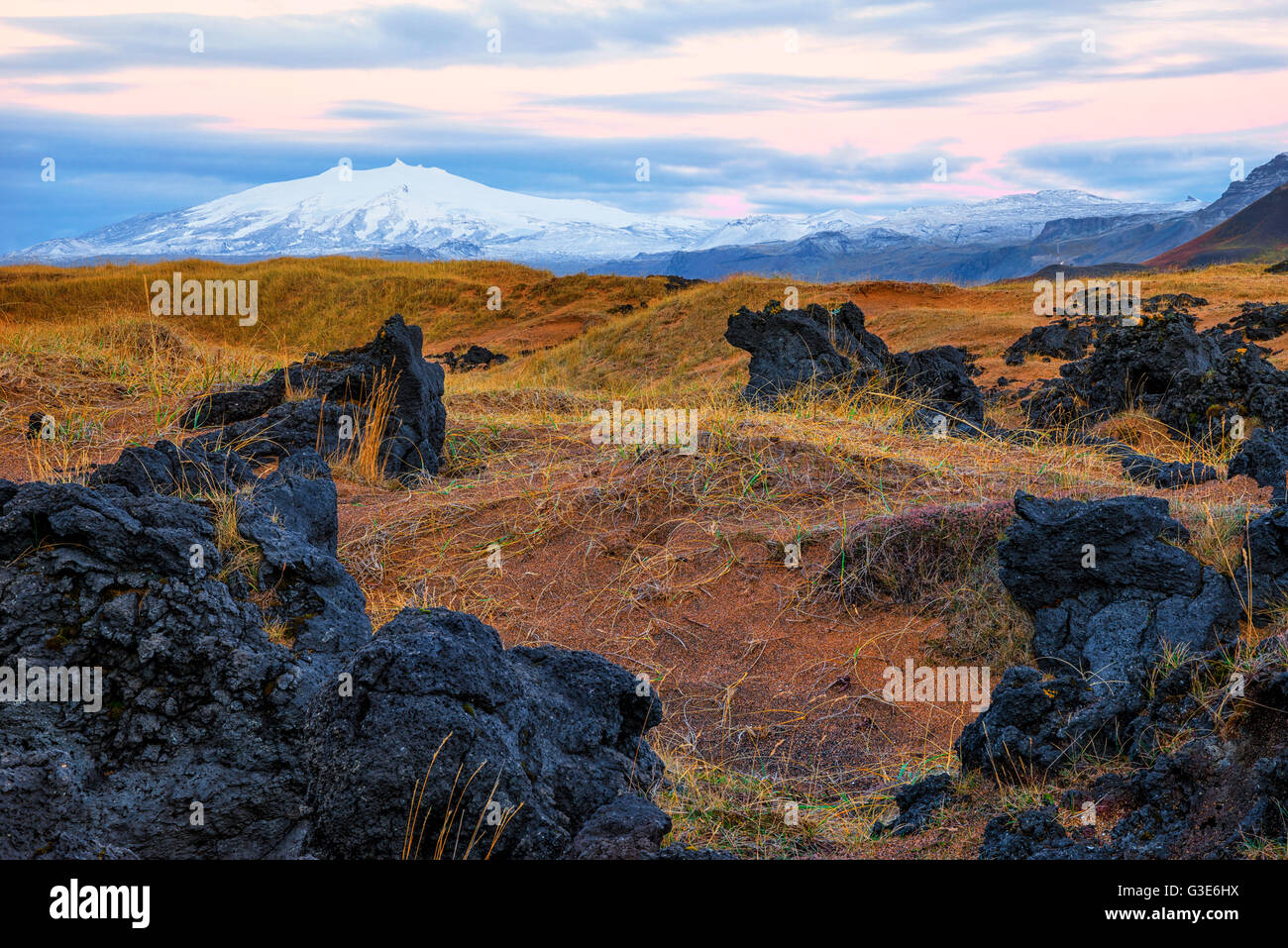Snaefellsjokull si innalza al di sopra del paesaggio circostante in Islanda della penisola Snaefellsness, con il sorgere del sole che illumina il cielo; Islanda Foto Stock