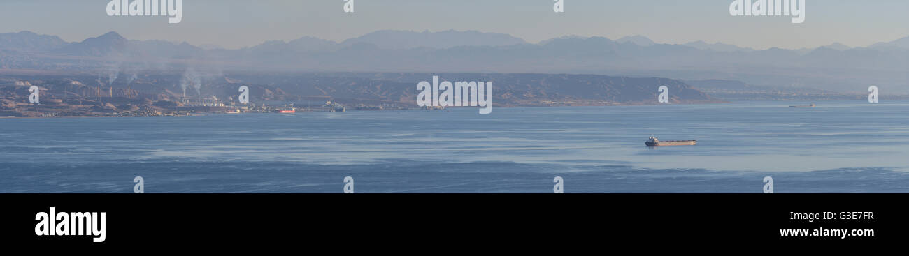 Seascape panorama feat. distante un bulk carrier e un litorale in background, Golfo di Aqaba, al largo della costa di Taba, Egitto Foto Stock