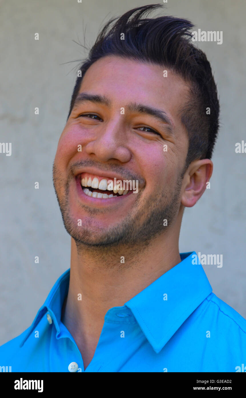 Ritratto di un bel giovane uomo ispanico sorridere e ridere e guardando molto felice Foto Stock