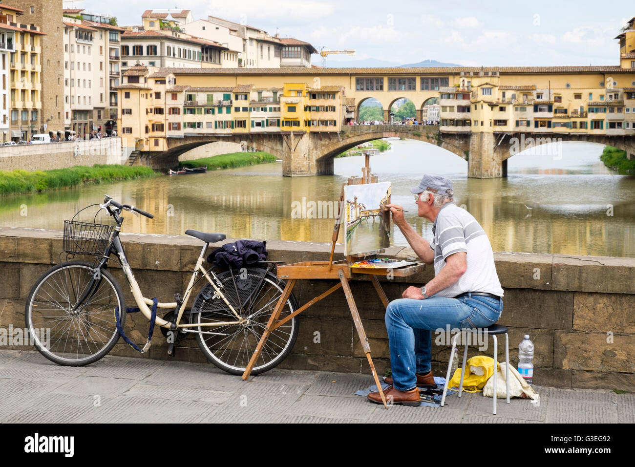 Un artista sul Ponte Santa Trinita in Firenze, Italia, lavorando su un dipinto del Ponte Vecchio visto in background. Foto Stock