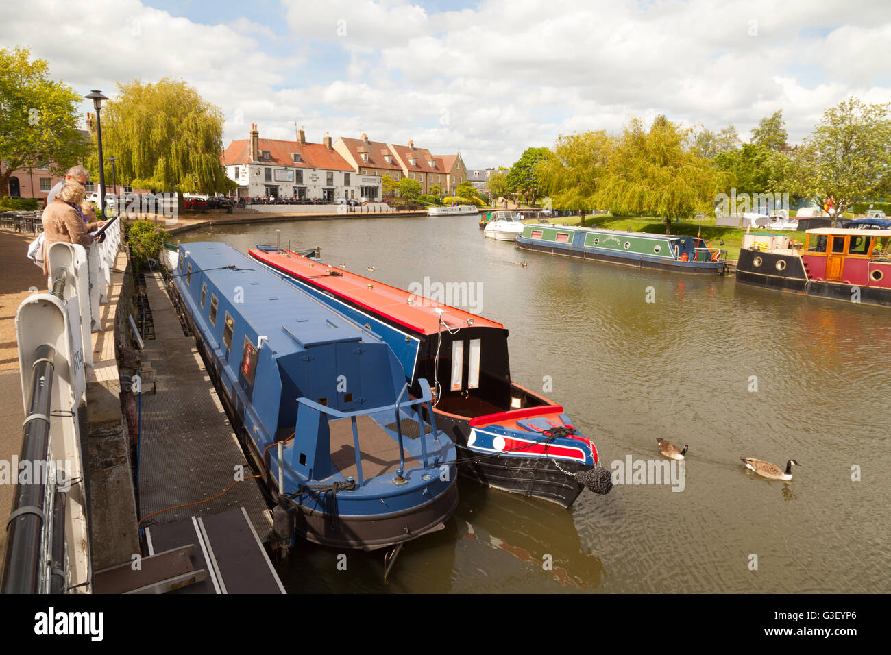 Persone che guardano le barche sul grande fiume Ouse su una giornata di primavera a Ely, Cambridgeshire East Anglia UK Foto Stock