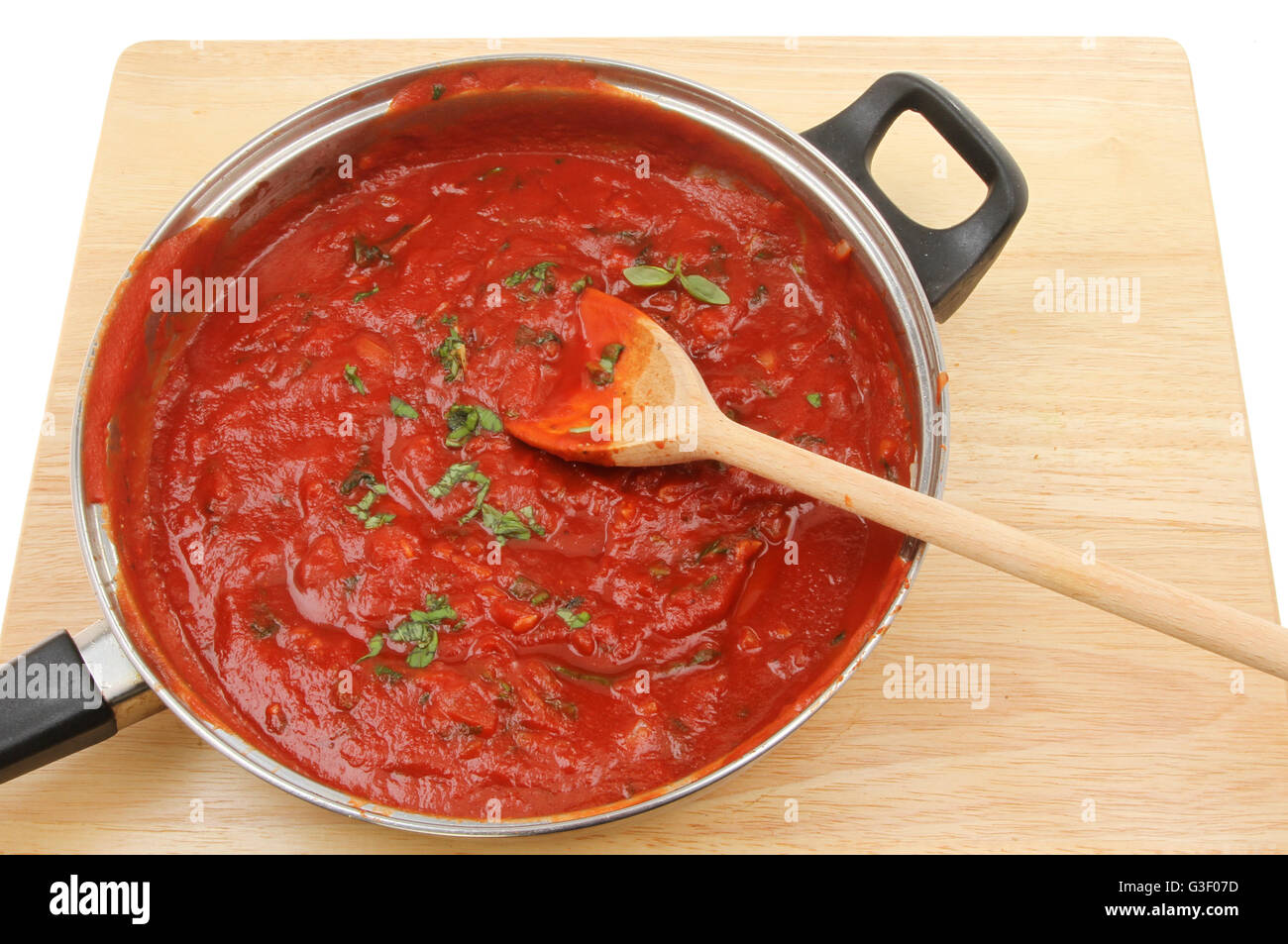 Pomodoro e Basilico salsa in una padella con un cucchiaio di legno su una tavola di legno Foto Stock