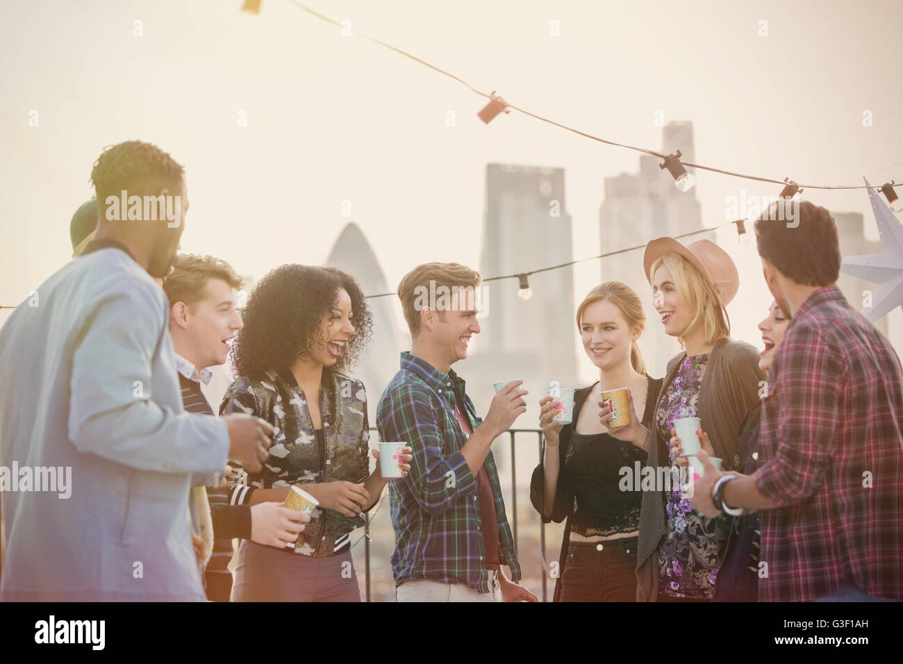Giovani amici adulti bere e godere di partito sul tetto Foto Stock