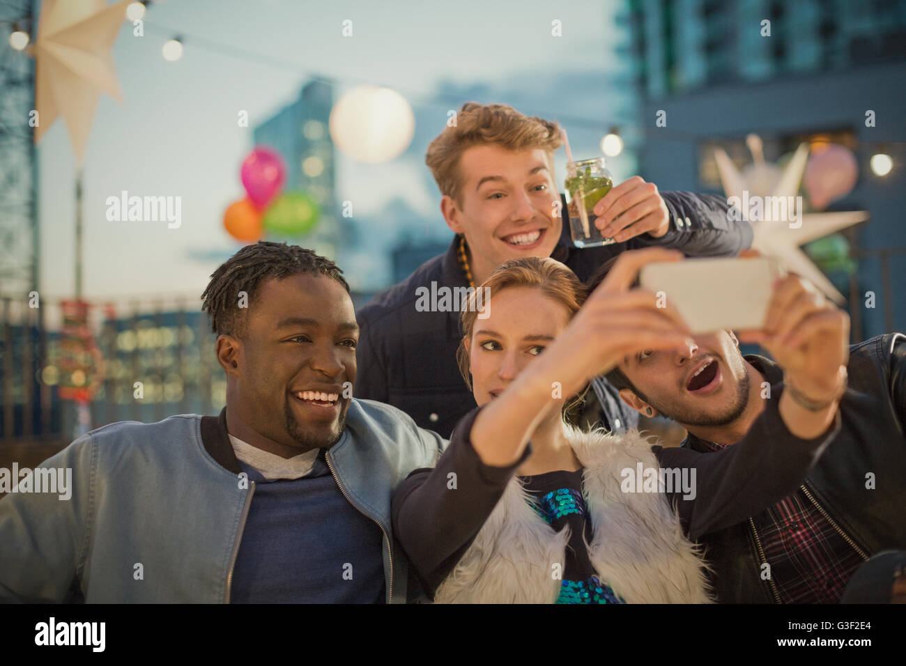 Giovani amici adulti tenendo selfie al partito sul tetto Foto Stock