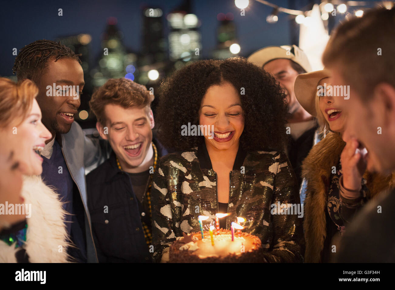 Amici celebrare la giovane donna il compleanno con torta e candele Foto Stock