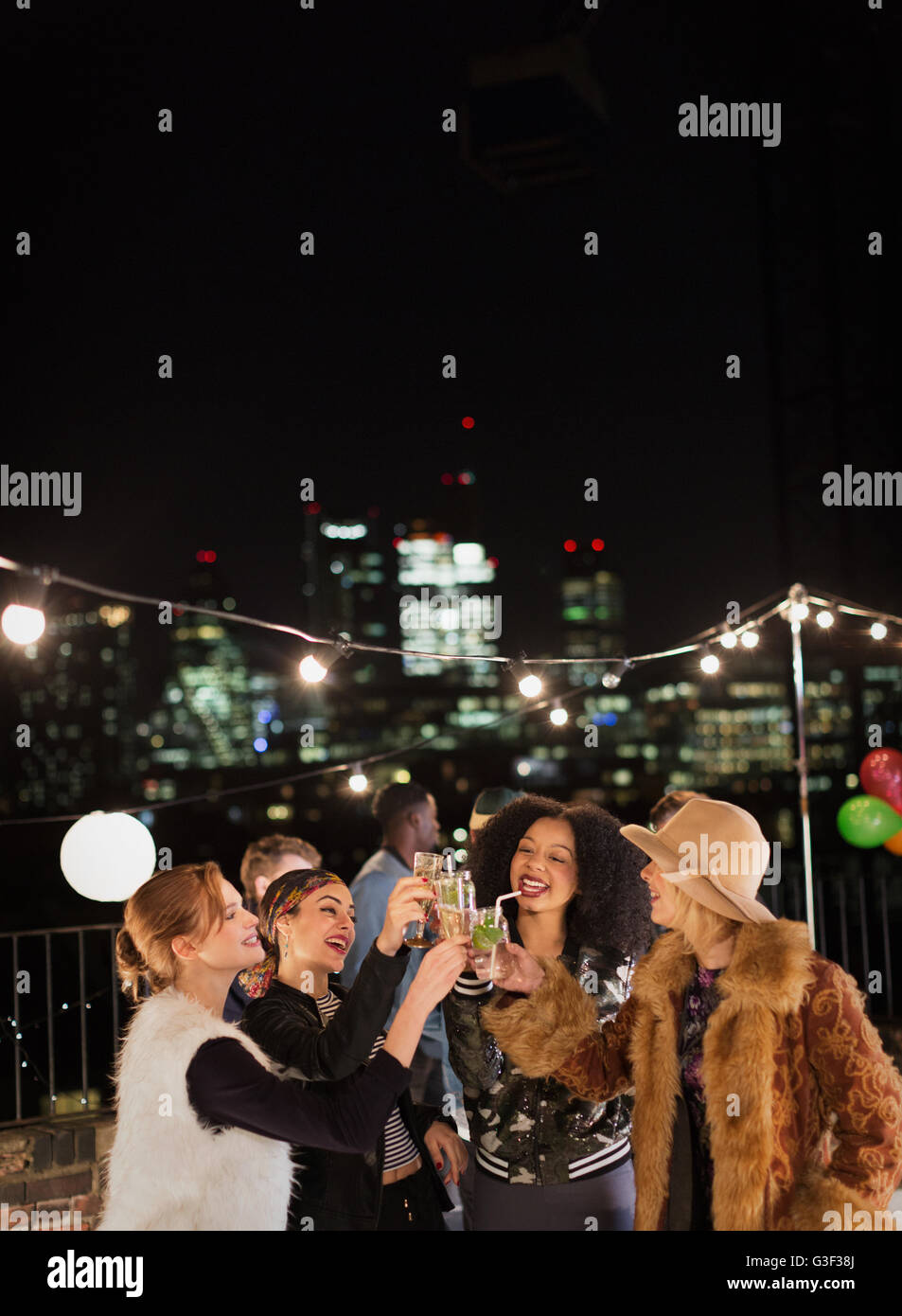 Giovani donne cocktail di tostatura in notturna Partito sul tetto Foto Stock