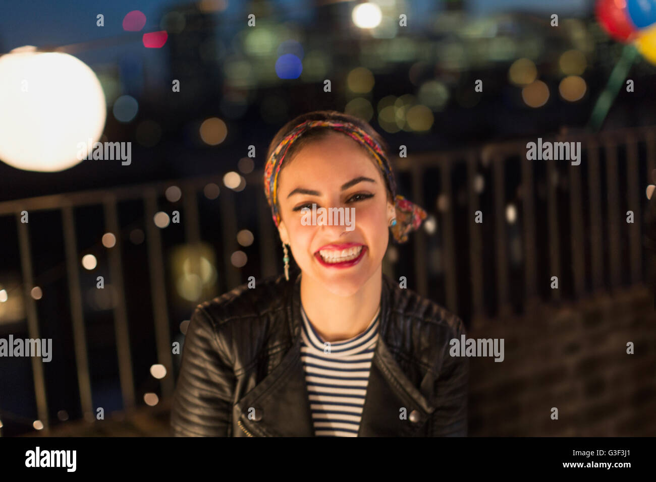 Ritratto sorridente giovane donna godendo di partito sul tetto Foto Stock