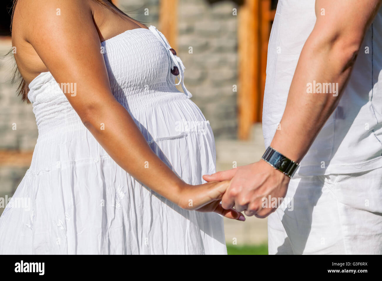 Felice dei genitori giovani in attesa di un bambino, donna incinta con il marito tenendo le mani nella natura Foto Stock