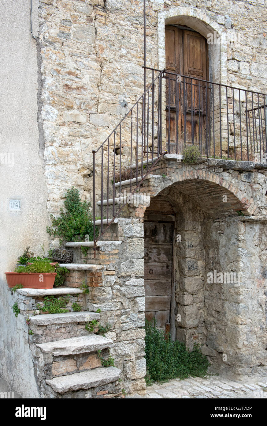 Pittoresca facciata di una vecchia casa in pietra con gradini in pietra avvolgimento su un arco in legno porta anteriore Foto Stock
