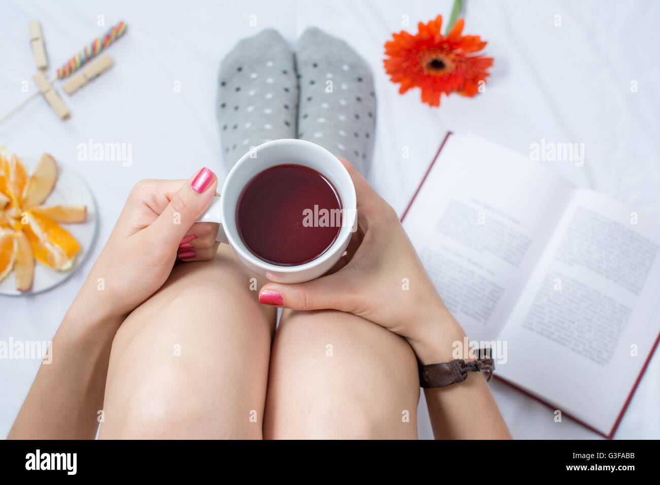 Donna che mantiene una tazza di tè nel letto Foto Stock