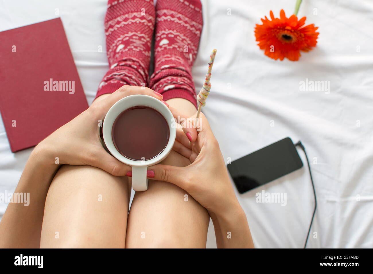 Donna con una tazza di tè per ascoltare musica a letto Foto Stock