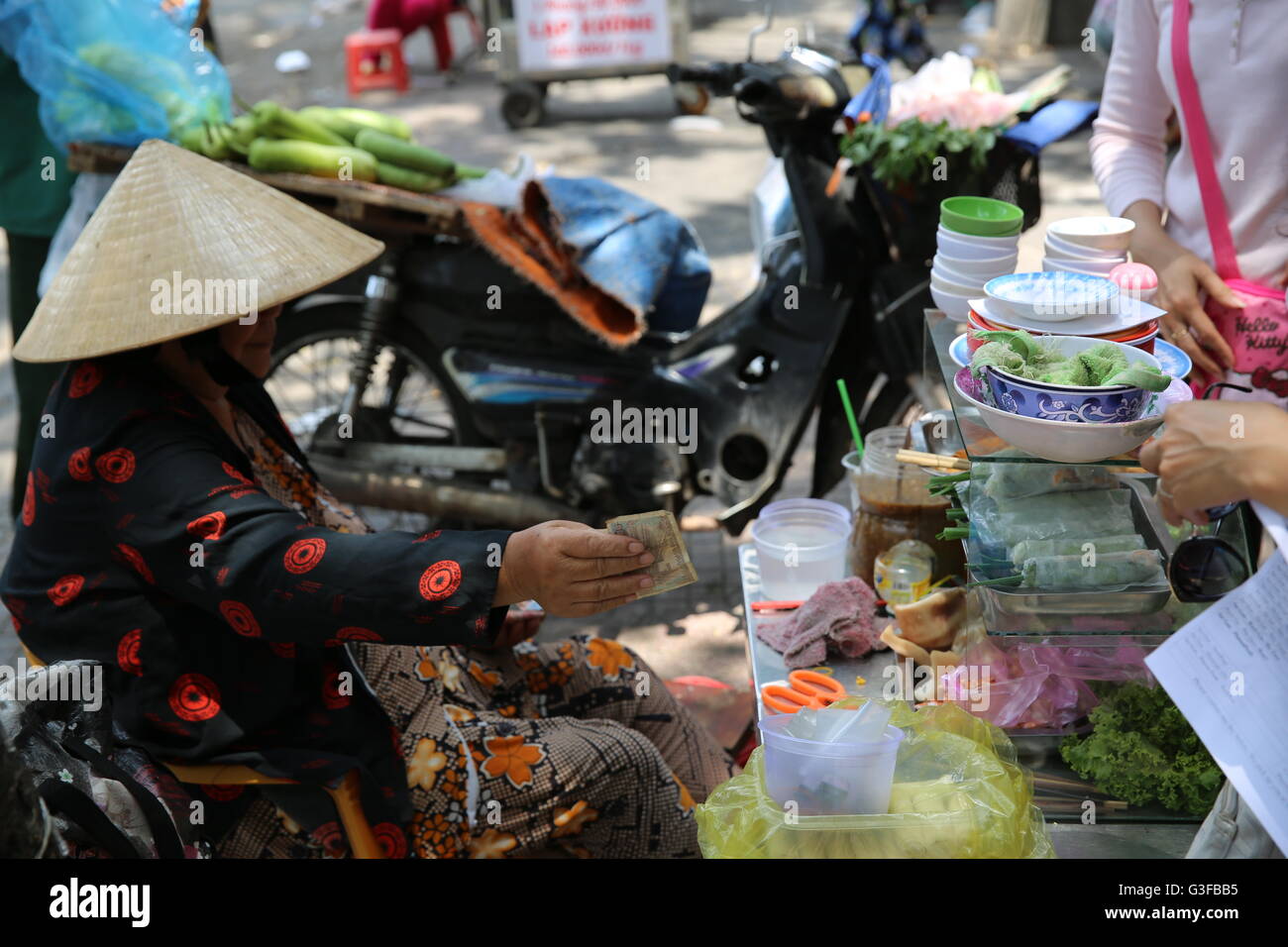 Donna vietnamita dando banconota cambiare per street cibo venduto a Saigon Foto Stock