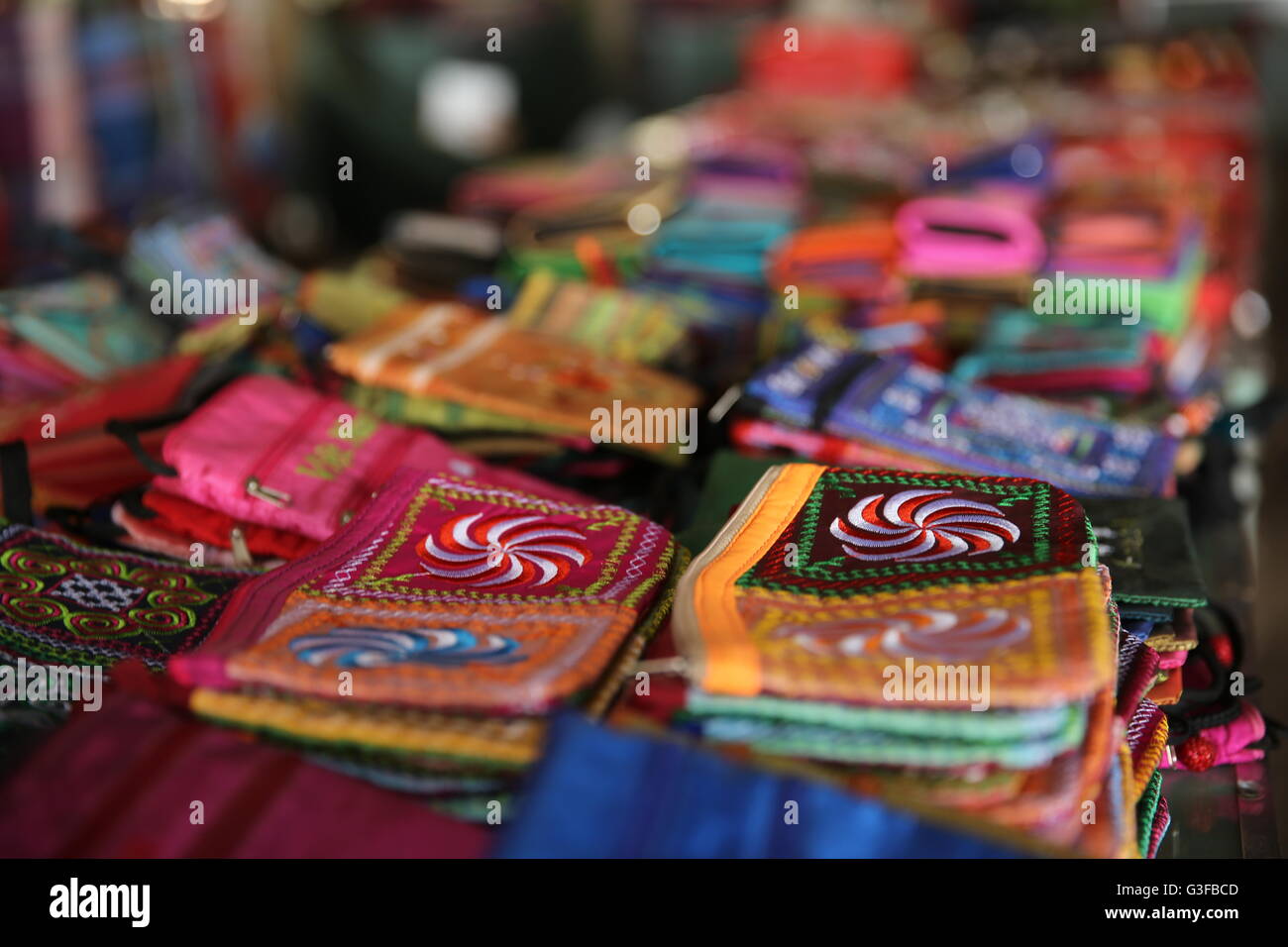 Piccole colorate portafogli zip impilati per la vendita in un mercato piccolo nel Delta del Mekong del Vietnam Foto Stock