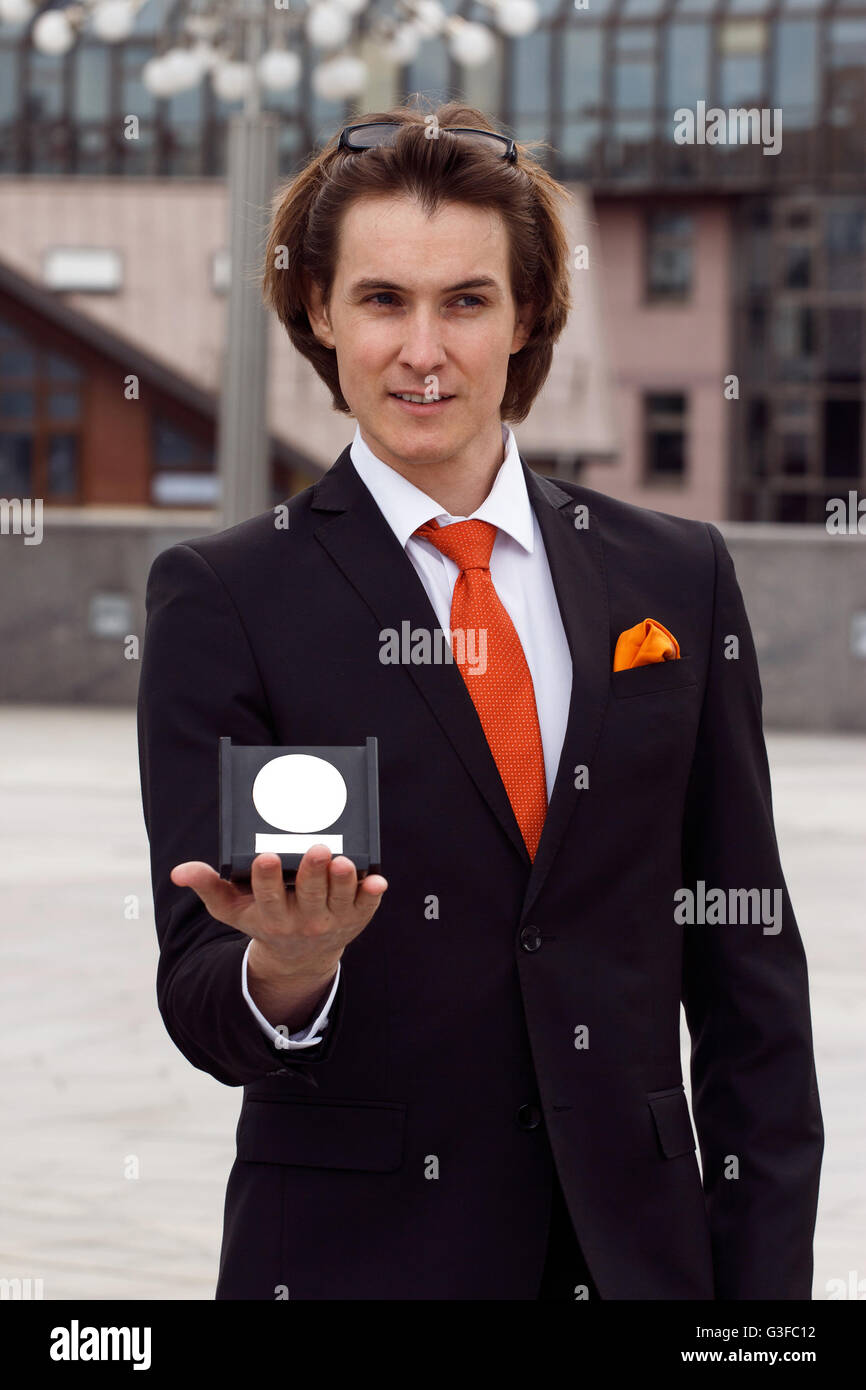 Imprenditore in un bellissimo vestito e cravatta arancione mostra il suo premio Foto Stock