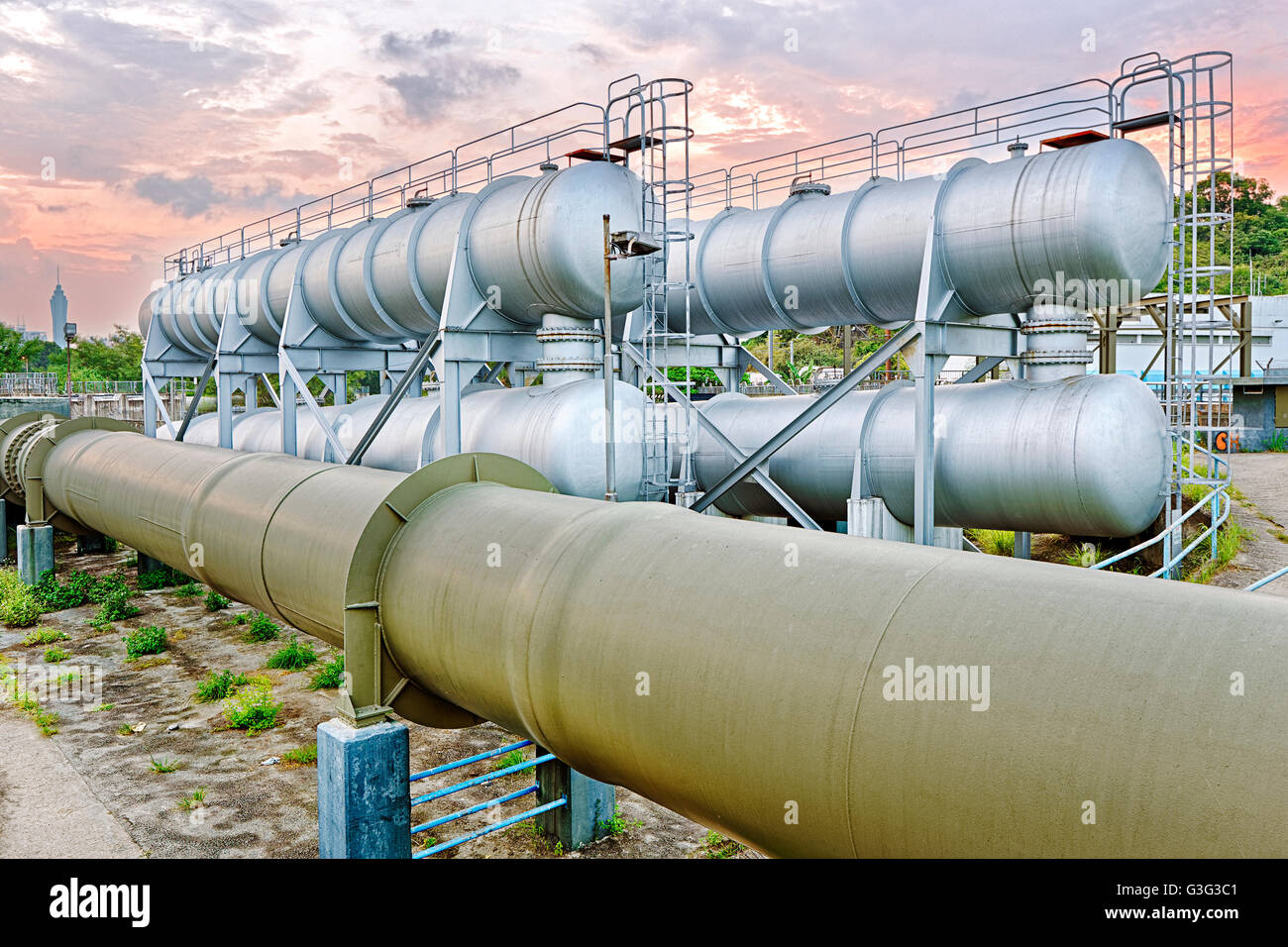 Industria petrolifera e del gas di raffineria in fabbrica al tramonto, impianto petrolchimico Foto Stock