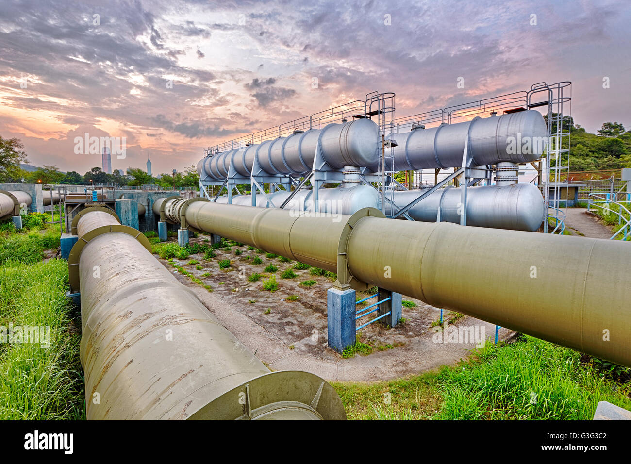Industria petrolifera e del gas di raffineria in fabbrica al tramonto, impianto petrolchimico Foto Stock