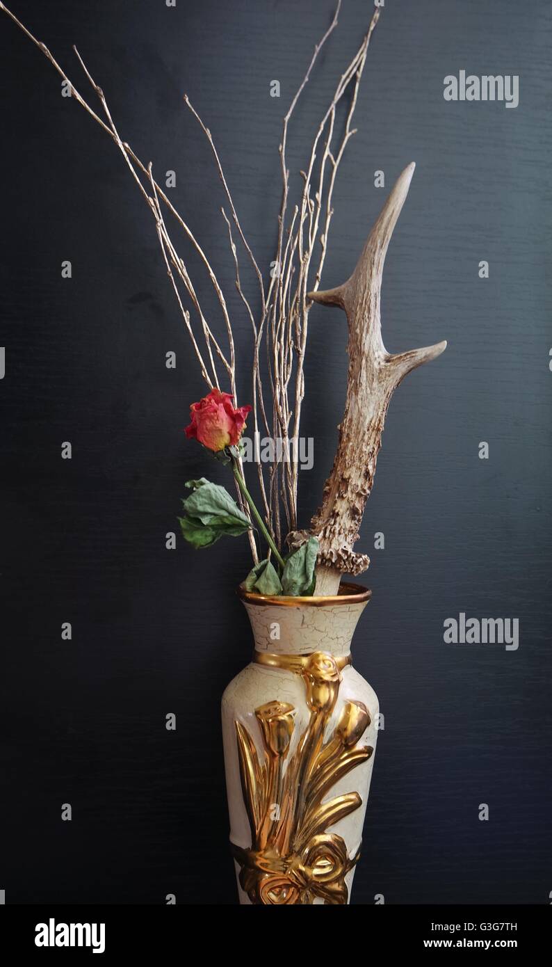 Natura morta rappresentata da una rosa cariati, un corno di cervo e oro dipinto di rami. Foto Stock