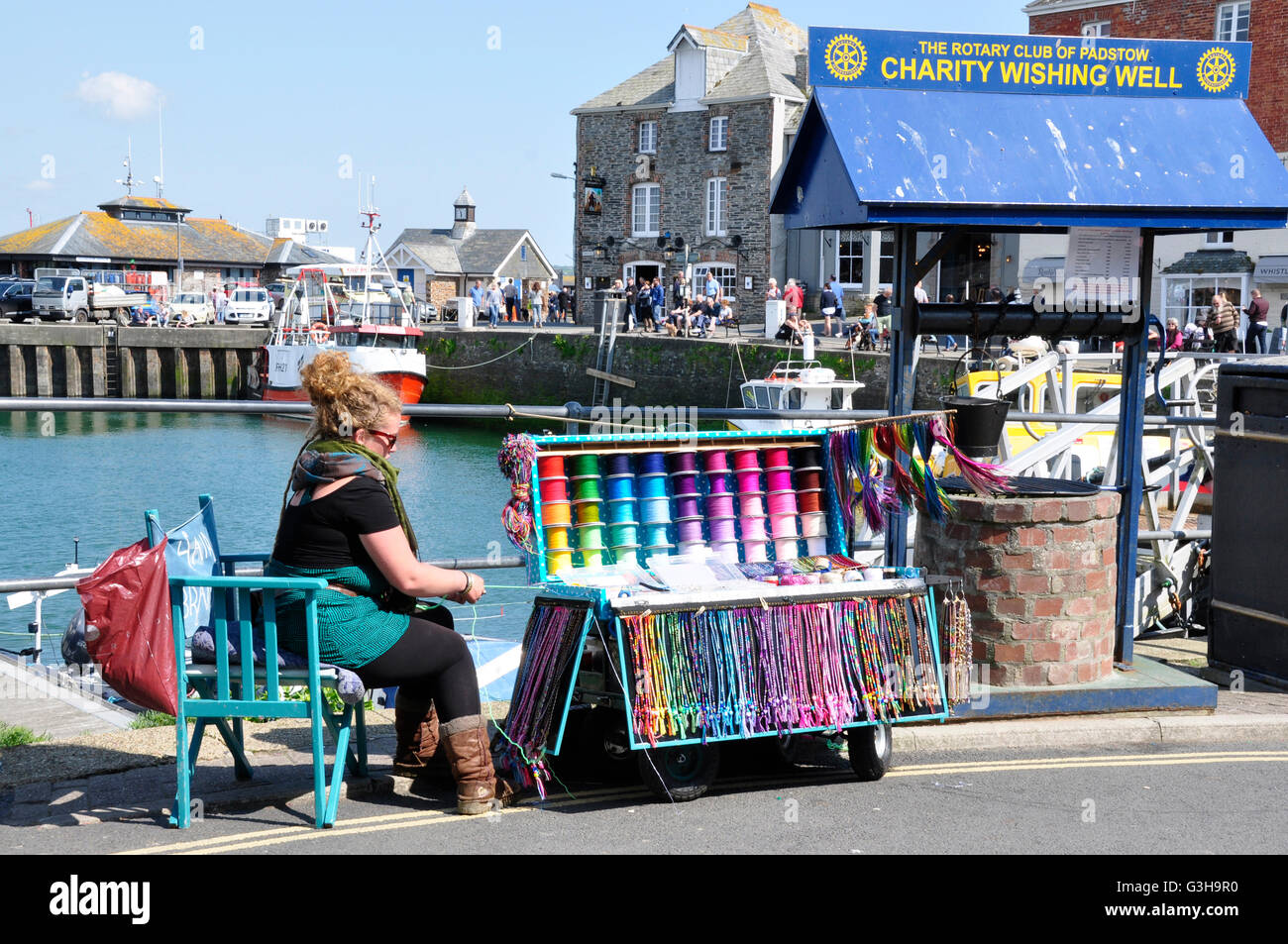 Cornwall - Padstow harbour - sulla banchina di amicizia braccialetto venditore - carità Wishing Well - colori brillanti - la luce del sole Foto Stock