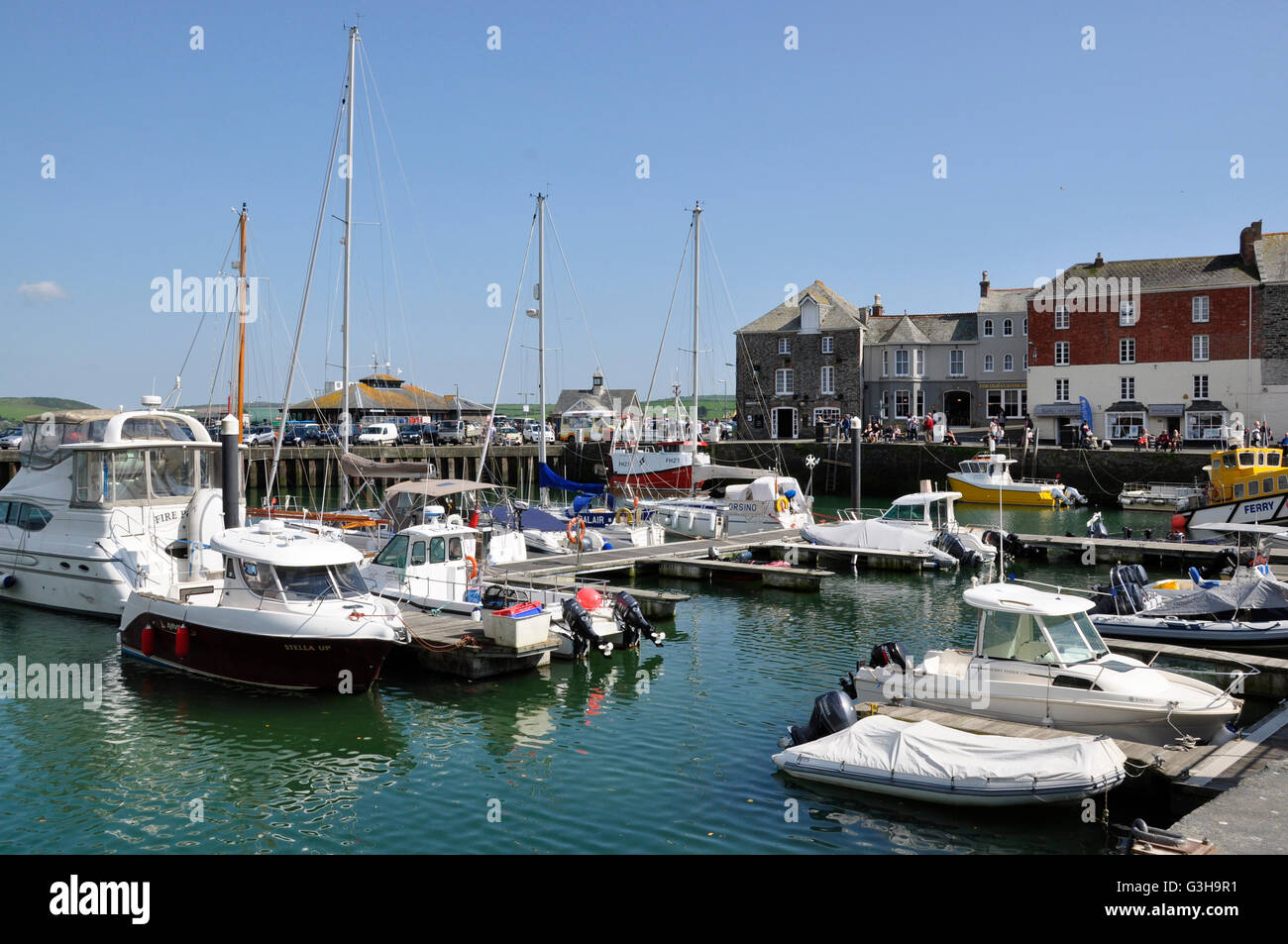 Padstow harbour - imbarcazioni da diporto a ancoraggio - edifici del periodo linea il quay - la luminosa luce del sole cielo blu - riflessioni Foto Stock