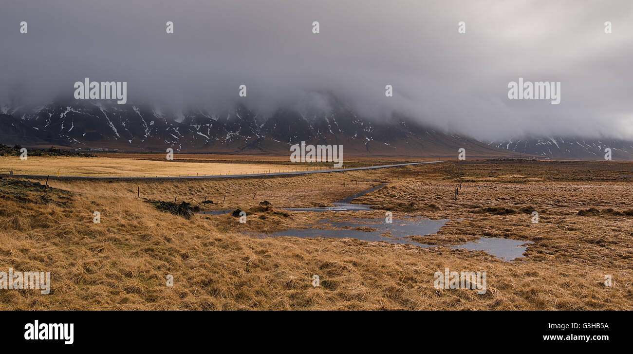 Drammatico tipico paesaggio islandese con vuoto su strada e montagne coperte con nebbia in Islanda. Foto Stock