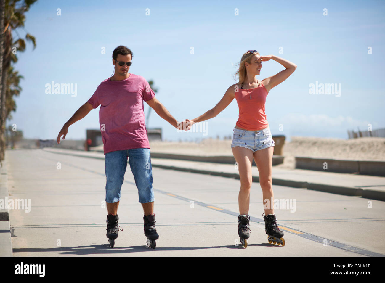Giovane con i rollerblade all'aperto, tenendo le mani Foto Stock