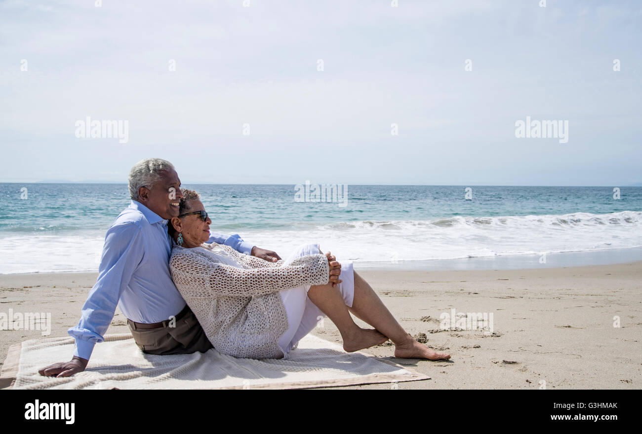 Coppia senior insieme rilassante sulla spiaggia, guardando a vista Foto Stock