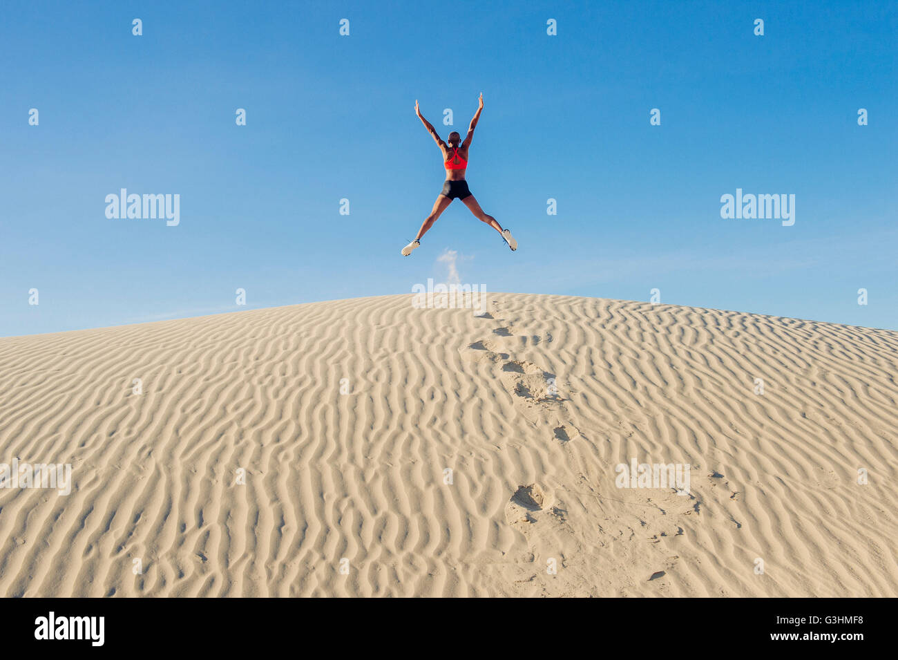 Runner il salto con le braccia e le gambe tese nel deserto, Death Valley, California, Stati Uniti d'America Foto Stock