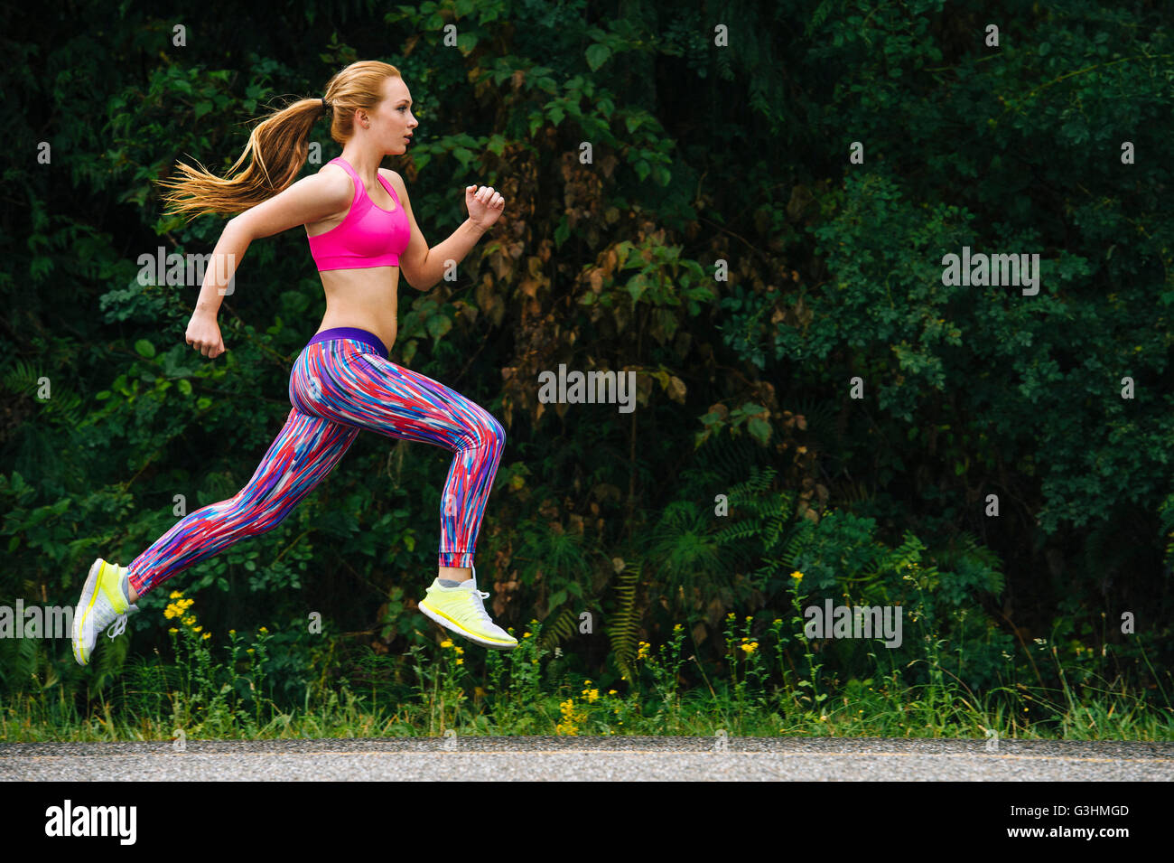 Femmina adolescente runner in esecuzione su strada rurale Foto Stock