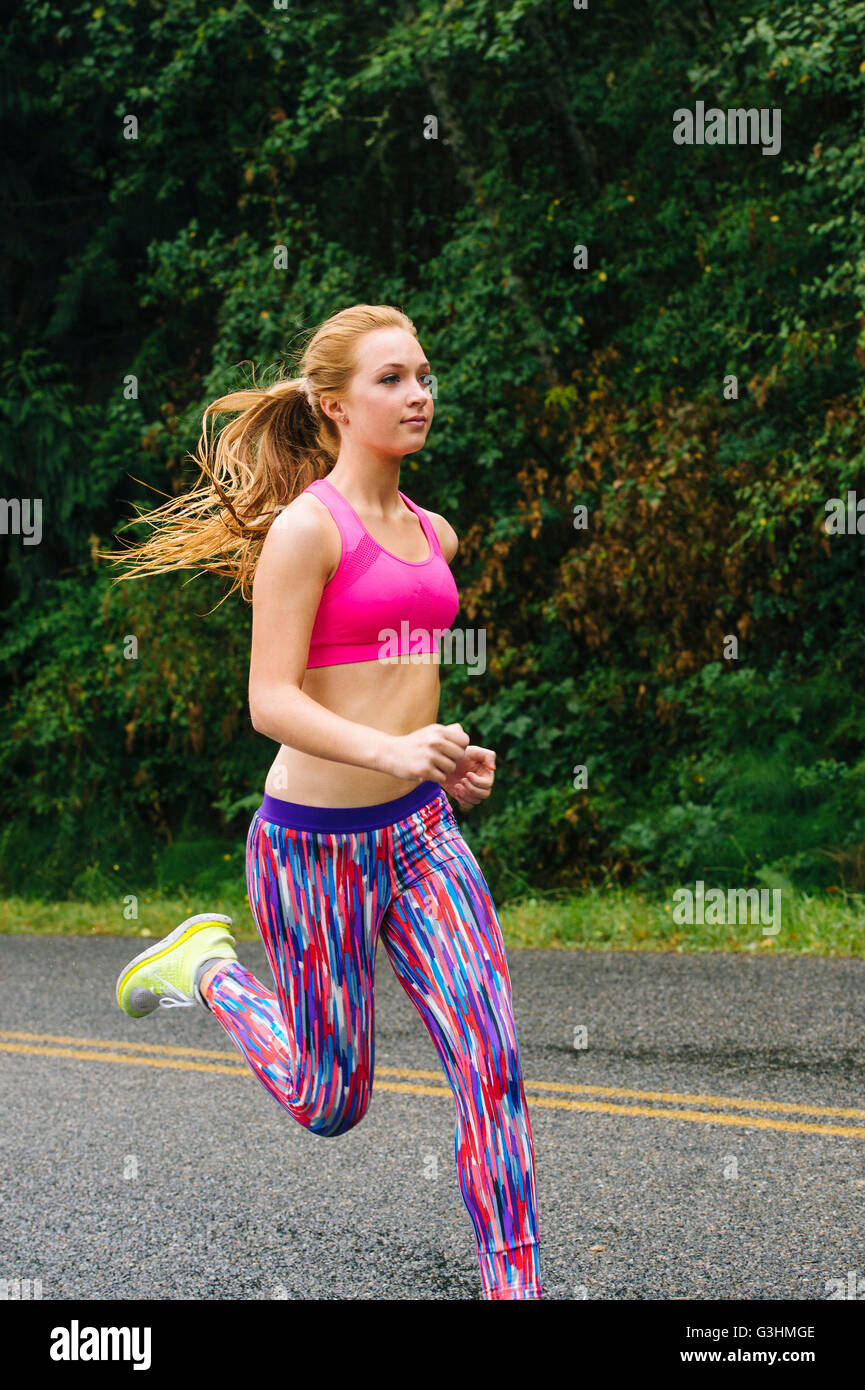 Femmina adolescente runner in esecuzione su strada rurale Foto Stock