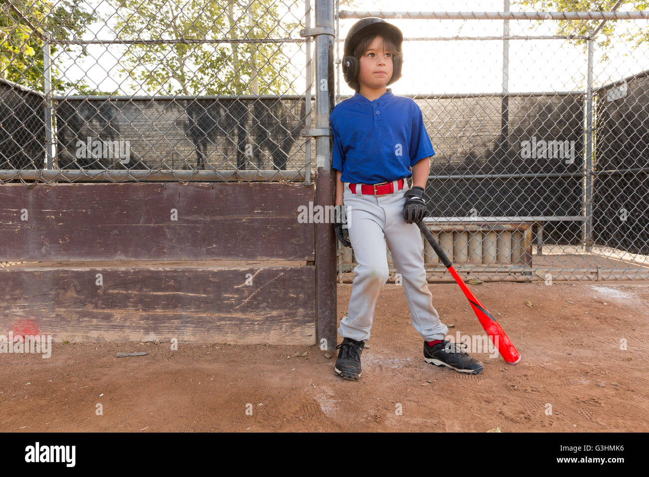 Ragazzo appoggiata contro la recinzione con la mazza da baseball in pratica sul campo di baseball Foto Stock