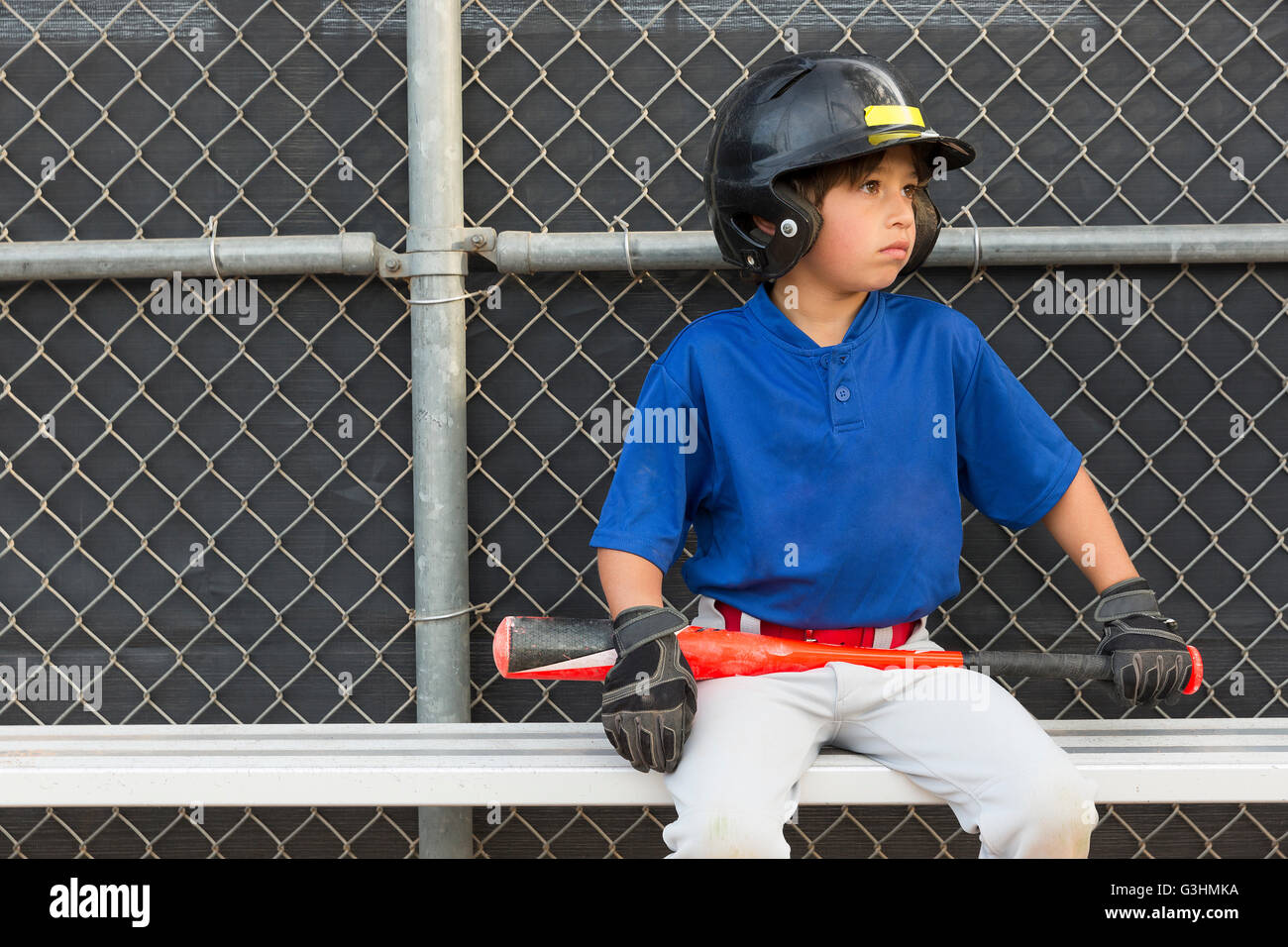 Ragazzo con la mazza da baseball guardando da banco a pratica di baseball Foto Stock