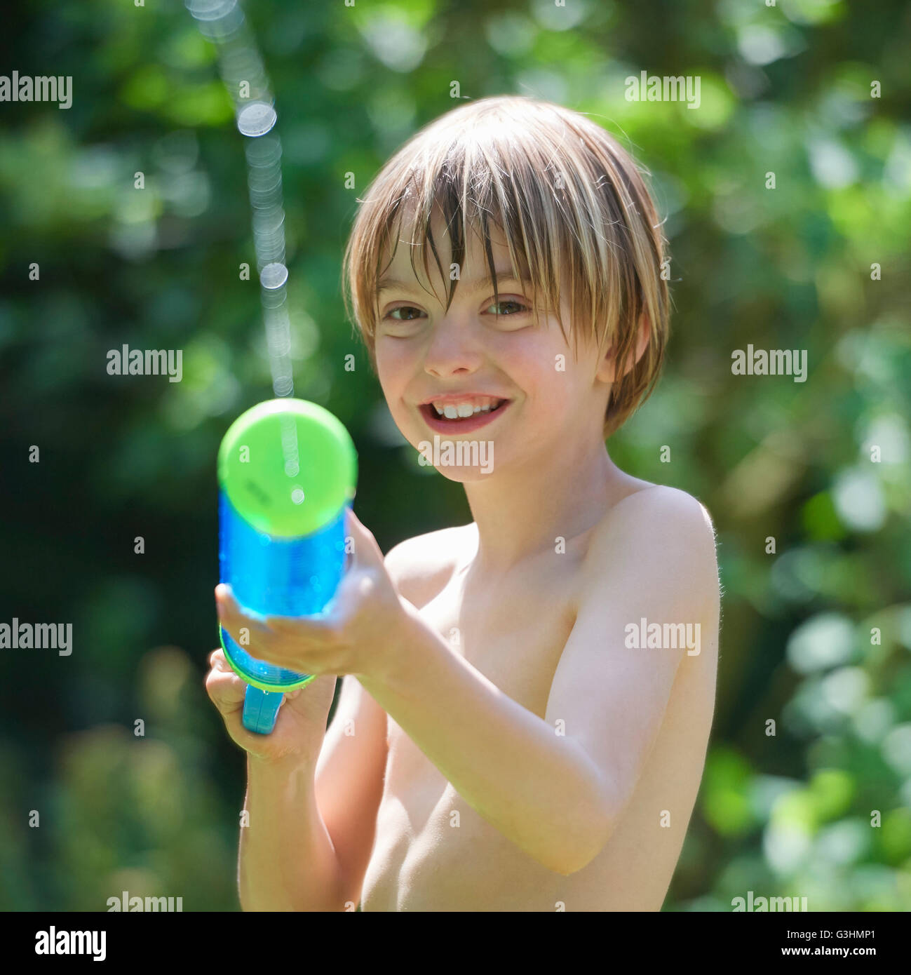 Ritratto di boy squirting pistola ad acqua in giardino Foto Stock
