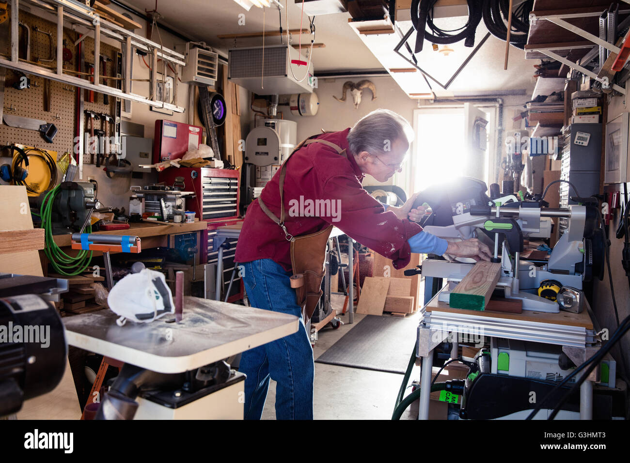 Senior uomo segare con la sega circolare nel laboratorio di falegnameria Foto Stock