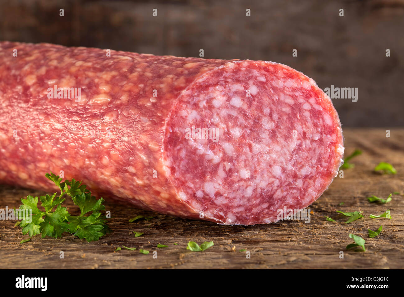 Fresco salame italiano sulla tavola di legno con erbe aromatiche Foto Stock